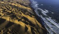 Aerial view of the sand dunes of the Namib Desert colliding with the Atlantic Ocean